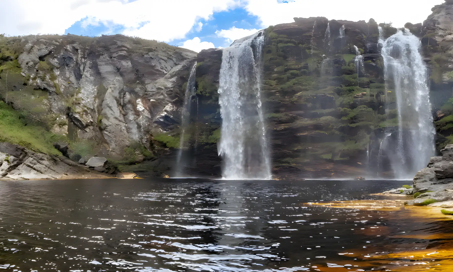 Cachoeira caindo de paredão de pedra em um poço de águas escuras