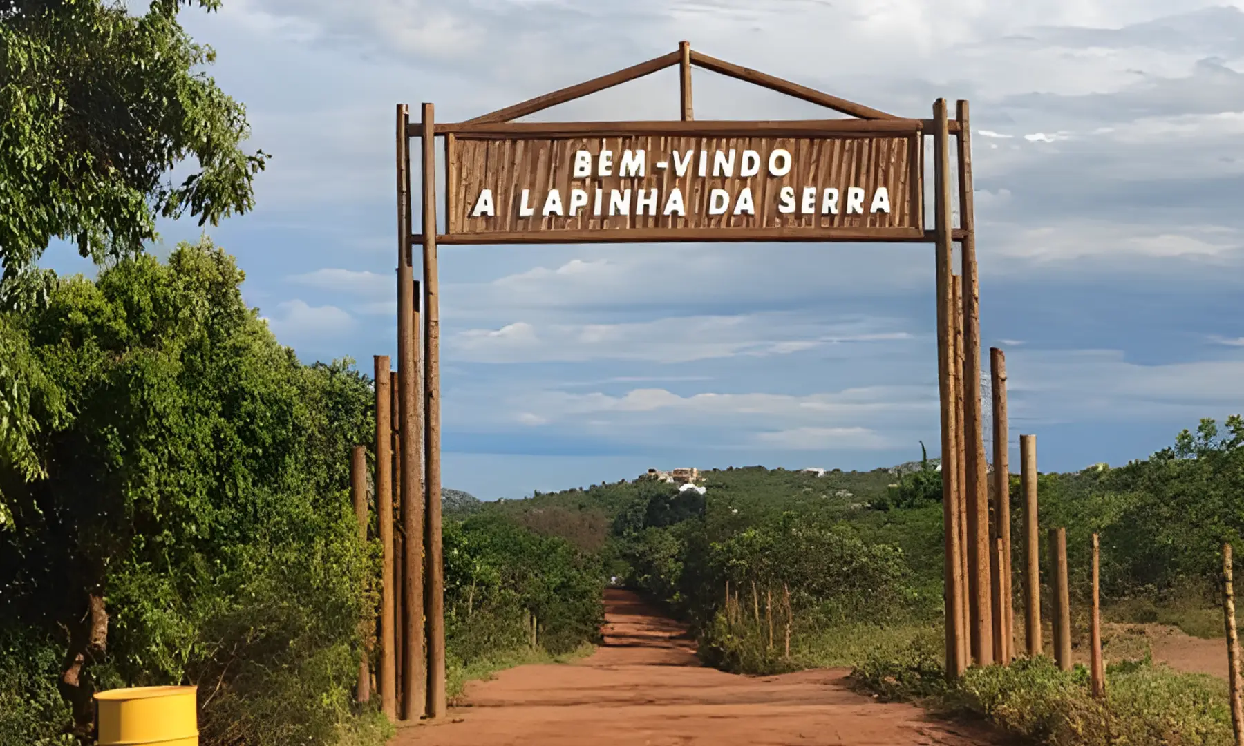 Portal de madeira com os dizeres Bem-vindo à Lapinha da Serra na estrada de terra
