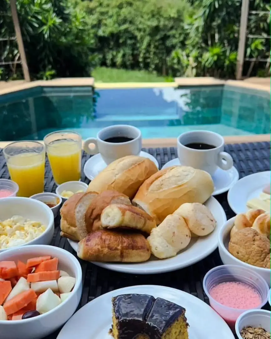 Café da manhã servido à beira da piscina: pães, frutas, sucos e café