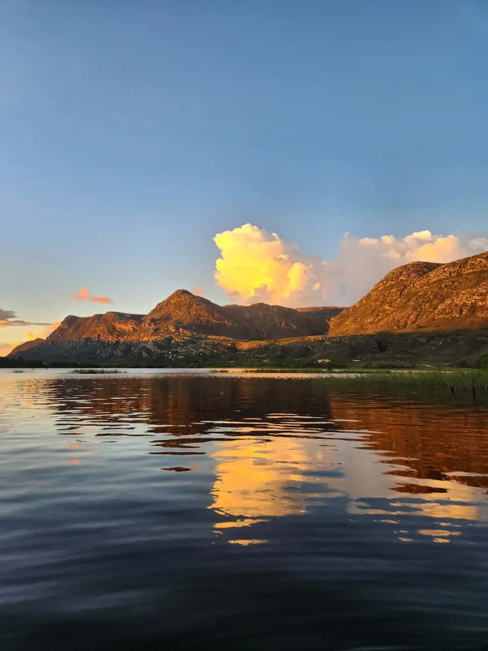 Montanhas da Lapinha da Serra iluminadas pelo entardecer e refletidas na lagoa